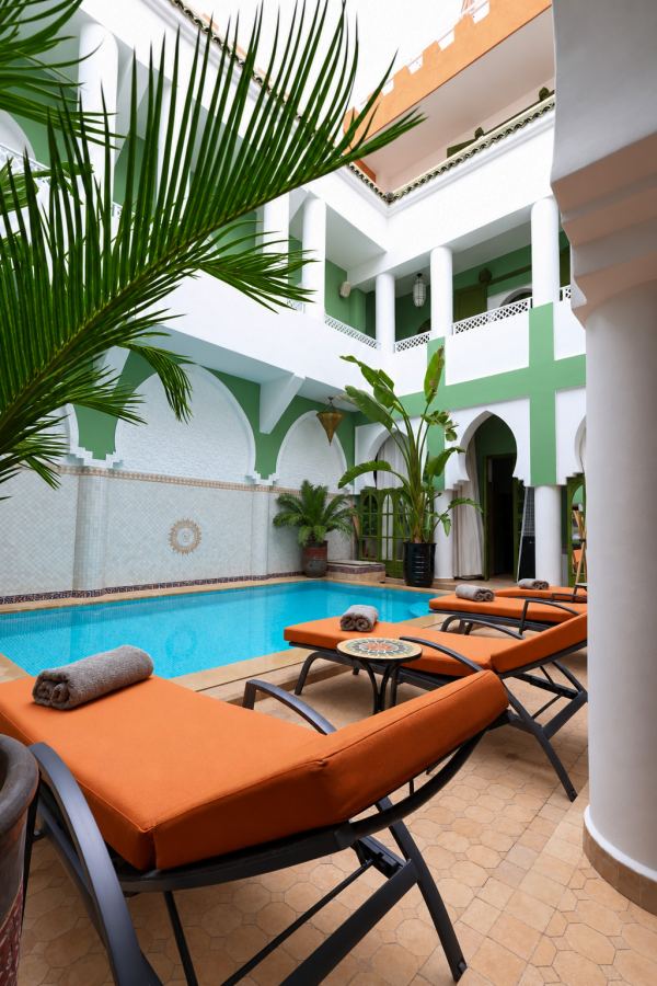 La piscine chauff&eacute;e sous les palmiers du patio